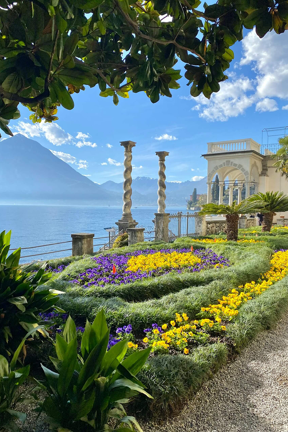 北イタリア・コモ湖畔のヴィラ庭園に咲く黄と紫の花々とクラシカルな螺旋柱、湖と山々の絶景(コモ湖でのフォトウェディング・ロケーション撮影 | Totte)