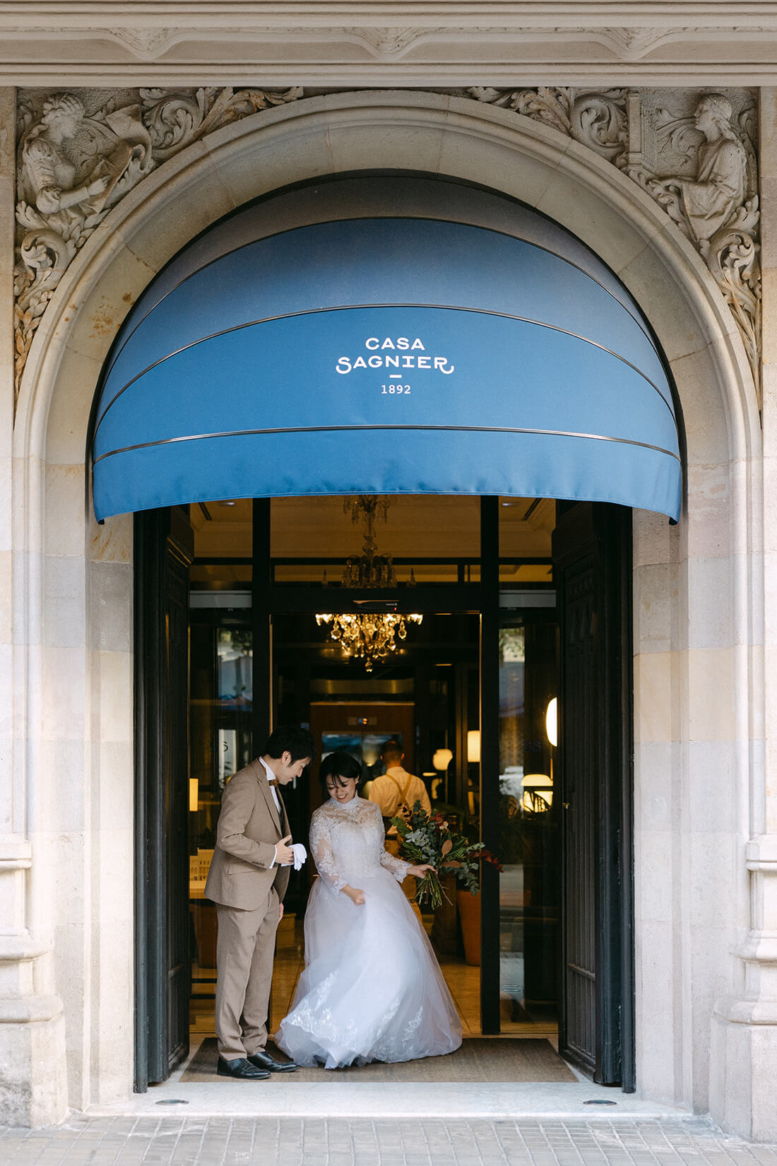 バルセロナの歴史的なブティックホテル「CASA SAGNIER（カサ・サニエ）」前で佇む新郎新婦。エレガントな建築美を背景にした、プレミアムなウェディングフォト。感度の高い大人のカップルにふさわしい、洗練されたバルセロナでのロケーション撮影。