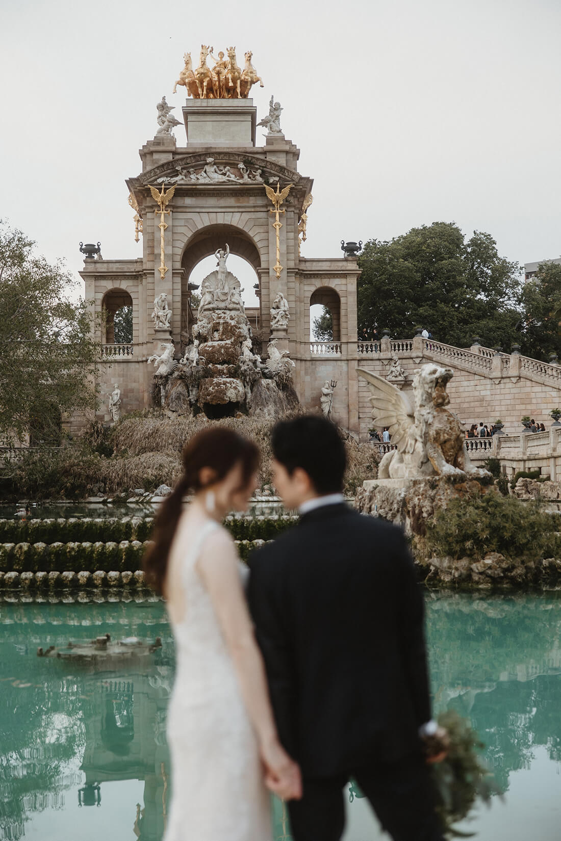 バルセロナ・シウタデリャ公園の壮大な大噴水をバックに手を繋ぎ見つめ合う新郎新婦のフォトウェディング | Totte