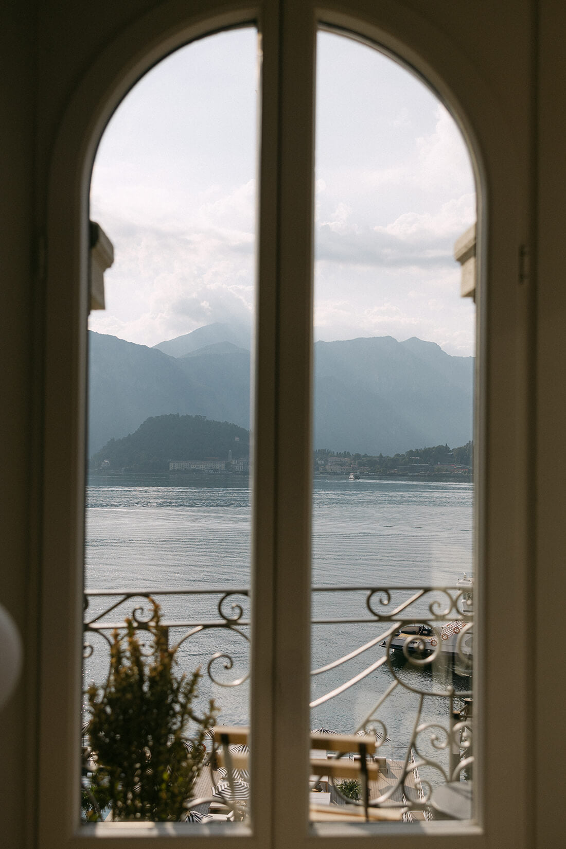 Totteのコモ湖ウェディングプラン「The Lake Como Edition」：ホテルスイートルームのクラシカルなアーチ窓越しに広がる静寂な湖と山々の絶景