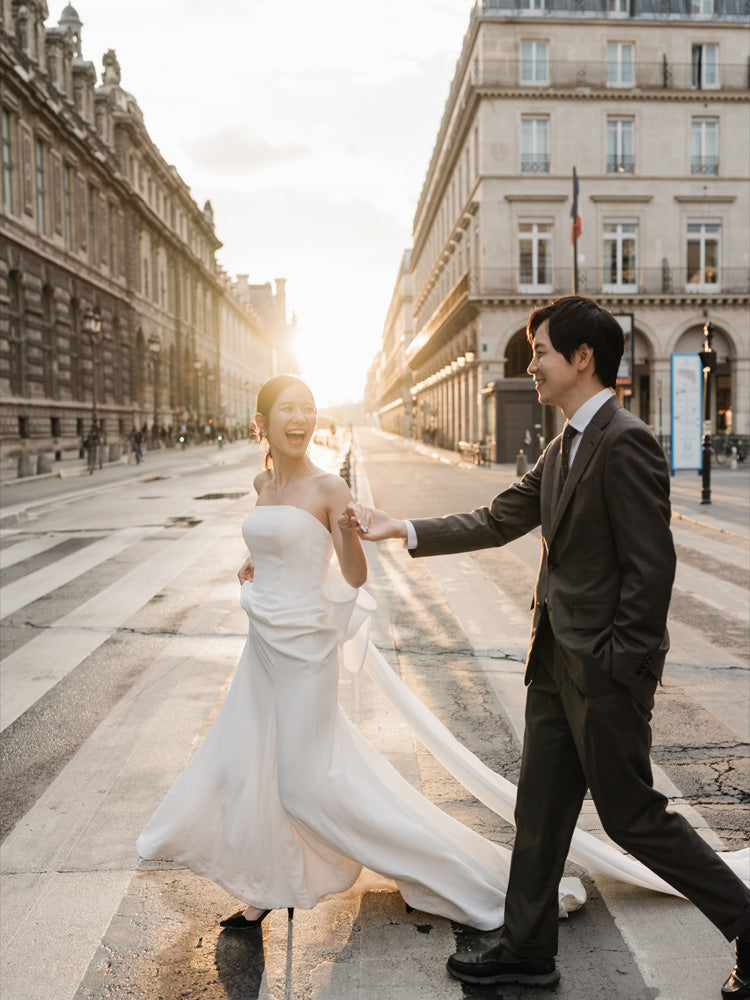 朝の柔らかな光が差し込むパリの街並みとエッフェル塔を背景に、寄り添い合うドレスとスーツ姿の新郎新婦。エレガントでロマンチックな雰囲気漂うパリの海外ウェディングフォト