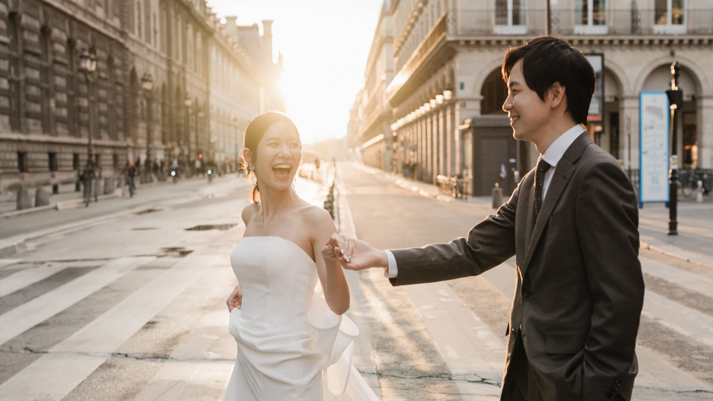朝の柔らかな光が差し込むパリの街並みとエッフェル塔を背景に、寄り添い合うドレスとスーツ姿の新郎新婦。エレガントでロマンチックな雰囲気漂うパリの海外ウェディングフォト