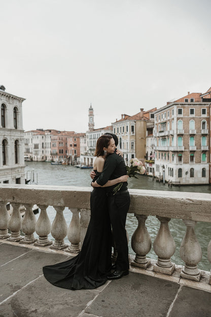 イタリア・ベネチアの象徴であるリアルト橋（Ponte di Rialto）の上で、大運河（カナル・グランデ）の絶景を背景に情熱的に抱き合う新郎新婦。活気ある運河の風景と二人の世界を対比させた、ELLE研修修了プランナー監修・Totteのドラマチックなフォトウェディング・ハネムーン撮影。